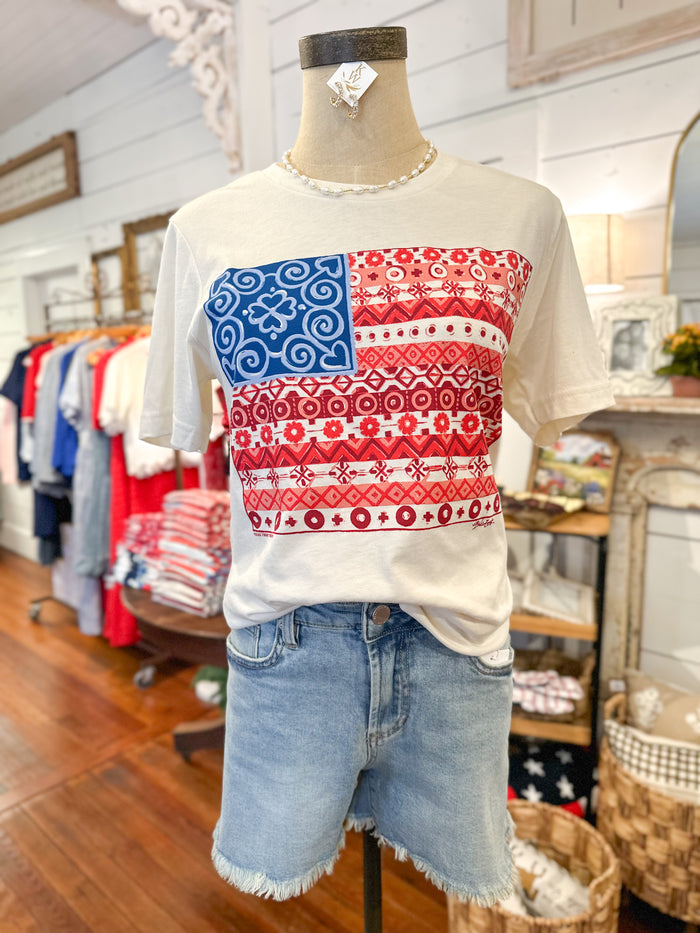 Mannequin wearing a white t-shirt with a red, white, and blue pattern in a store setting.