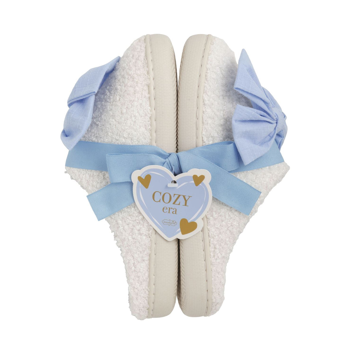 White slippers with blue bows and a 'Cozy Era' tag on a white background mud pie 