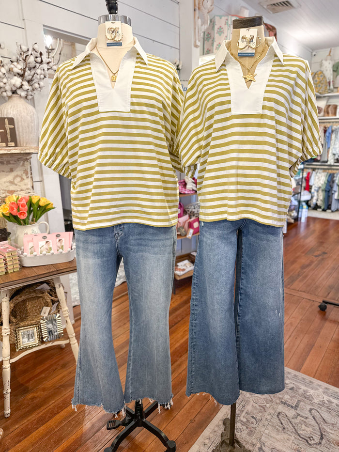 Two mannequins wearing green/ yellow striped shirts and blue jeans in a store setting.