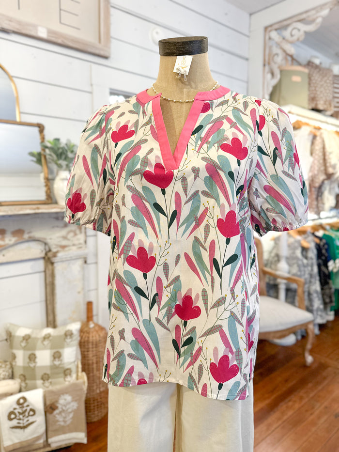Colorful floral-patterned blouse on a mannequin in a store setting