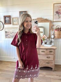 Woman taking a mirror selfie wearing a burgundy dress with lace trim in a home setting.