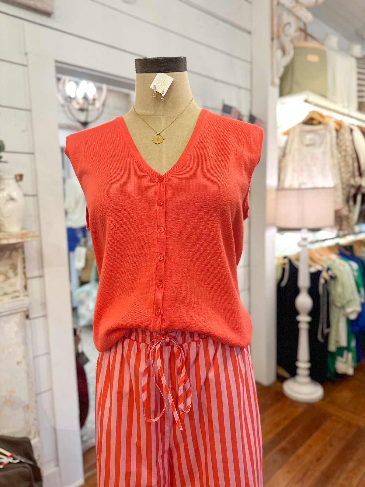 Mannequin wearing a coral sleeveless top and striped pants in a store setting