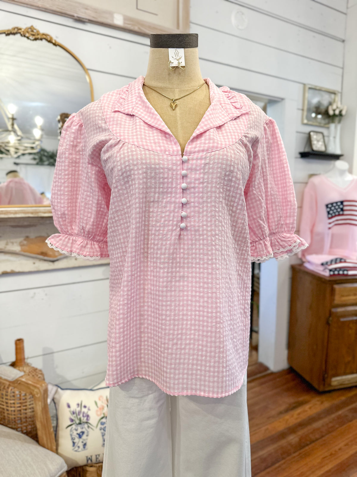 Mannequin wearing a pink checkered blouse in a store setting