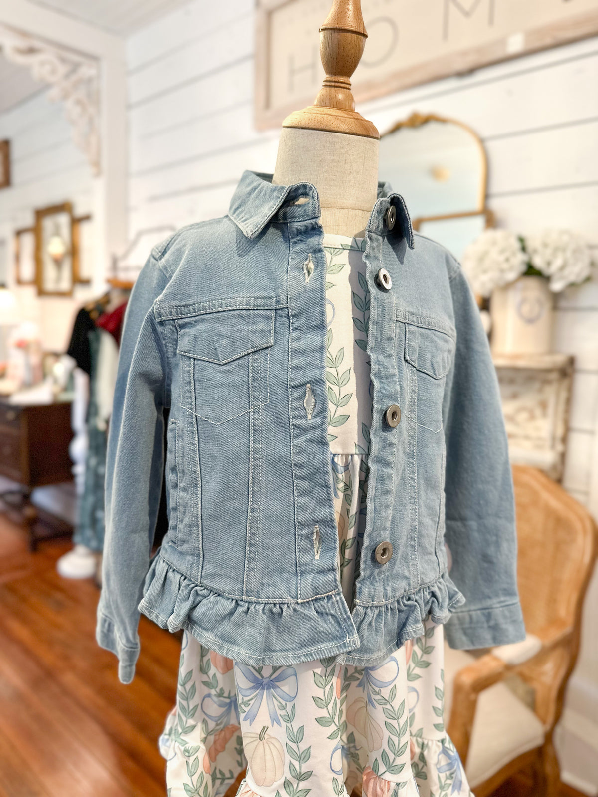 Denim jacket with ruffled details on a mannequin in a store setting for toddler girl 