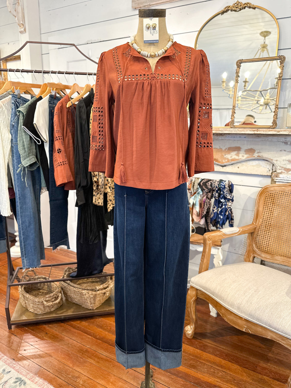 Mannequin wearing a rust-colored blouse and blue jeans in a clothing store
another love rust color top.