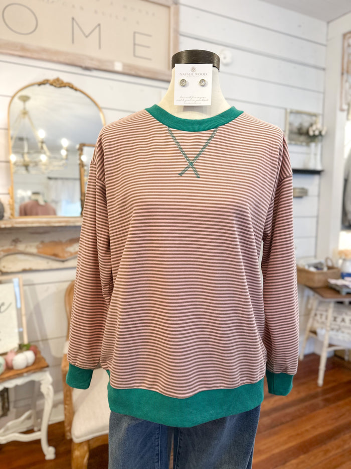 Striped sweater with green trim on a mannequin in a home decor setting