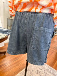 Blue denim shorts on a mannequin with an orange and white striped shirt in the background.