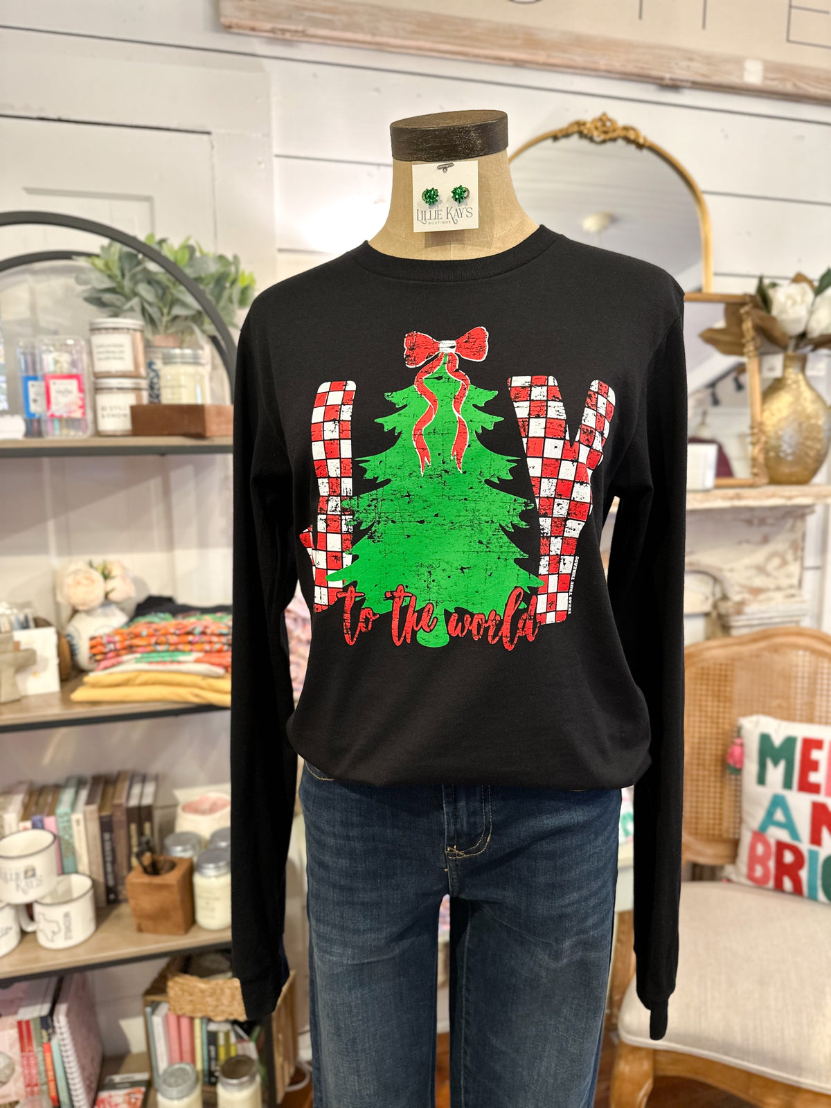 Black long-sleeve shirt with Christmas tree and candy cane design on a mannequin in a store setting.