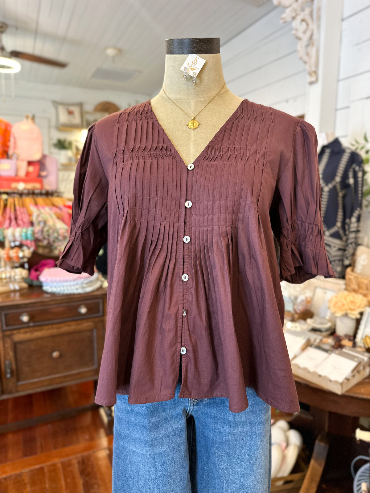 maroon blouse on a mannequin in a store setting