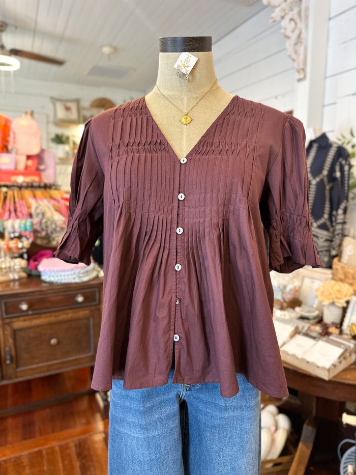 maroon blouse on a mannequin in a store setting