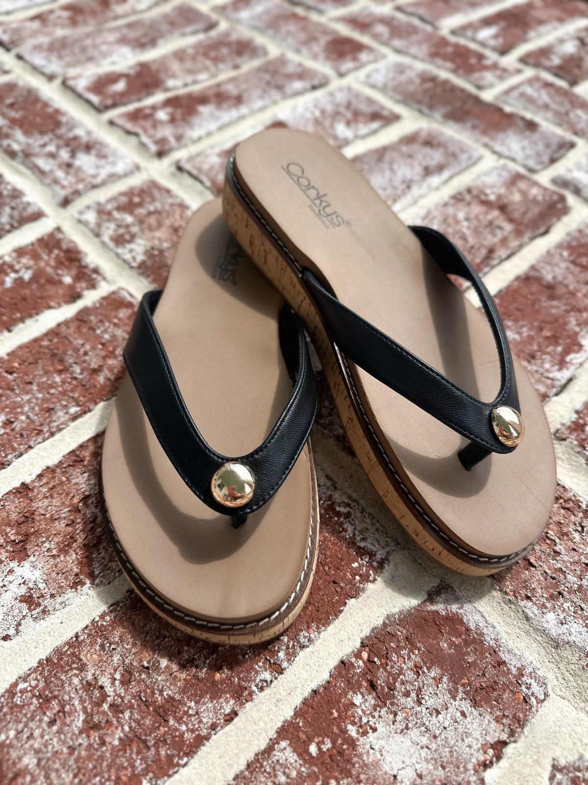 Pair of black and brown sandals on a brick surface