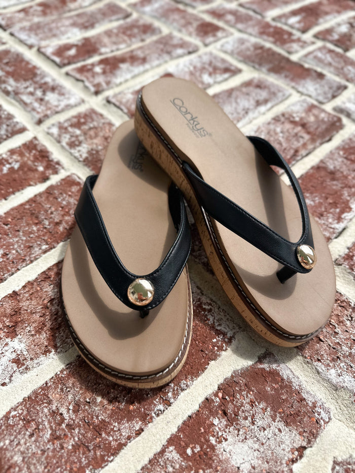 Pair of black and brown sandals on a brick surface