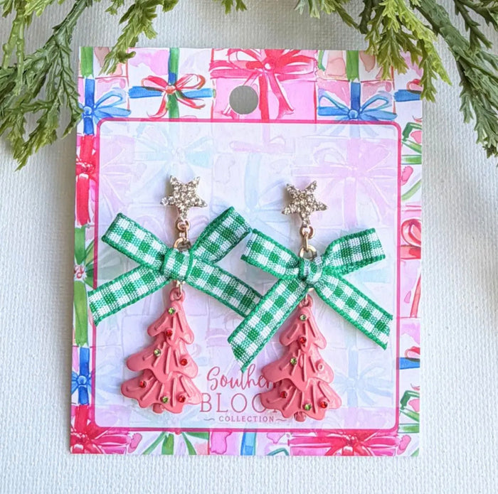 A pair of Christmas-themed dangle earrings displayed on their branded backing card. The earrings feature a green and white gingham ribbon bow with a gold-tone star charm above a pink plastic Christmas tree charm.