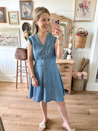 Woman taking a mirror selfie wearing a blue dress in a home setting.