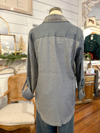 Mannequin wearing a checkered shirt in a store setting with various items in the background.