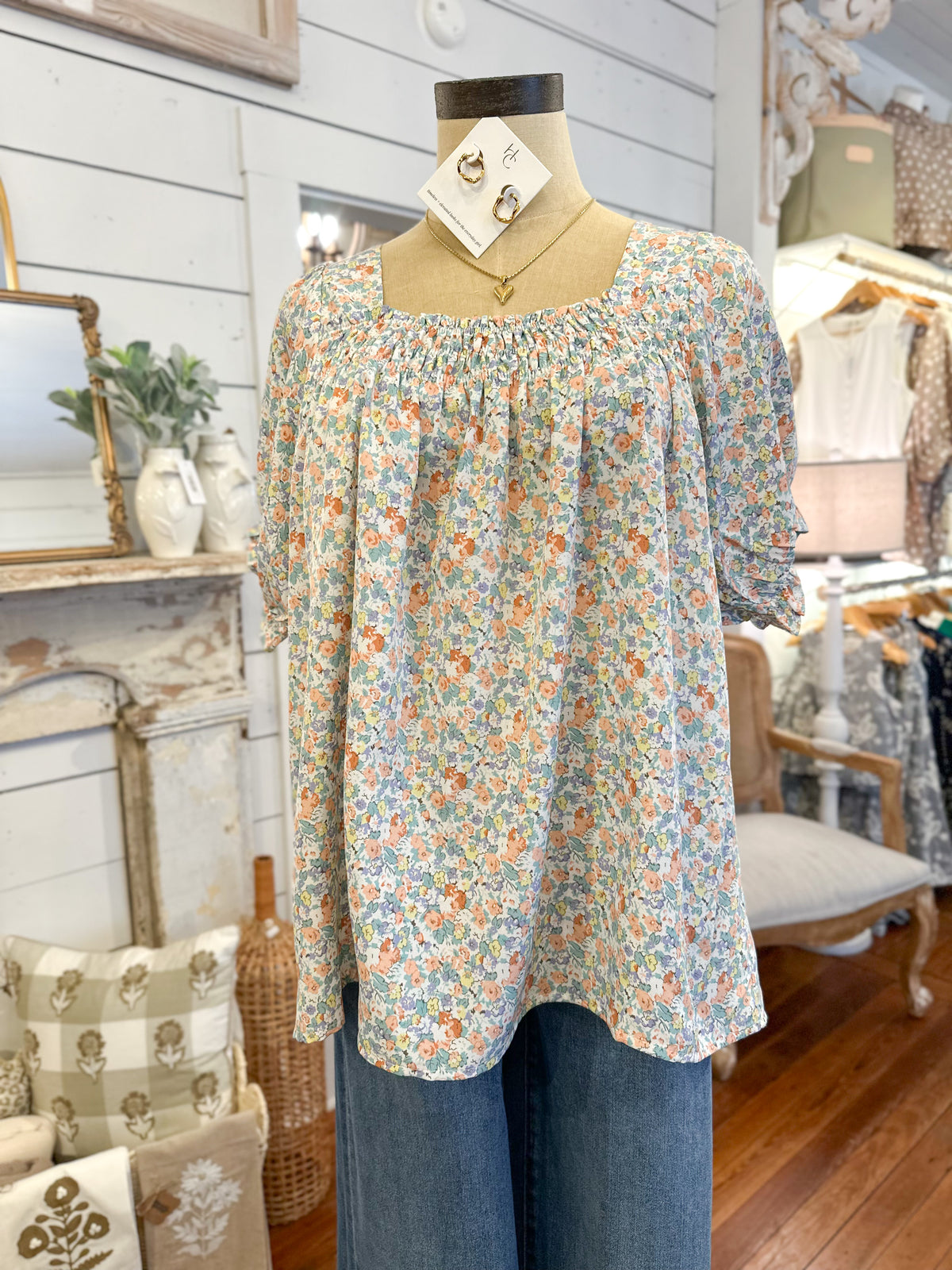 Floral blouse on a mannequin in a store setting with decor elements.