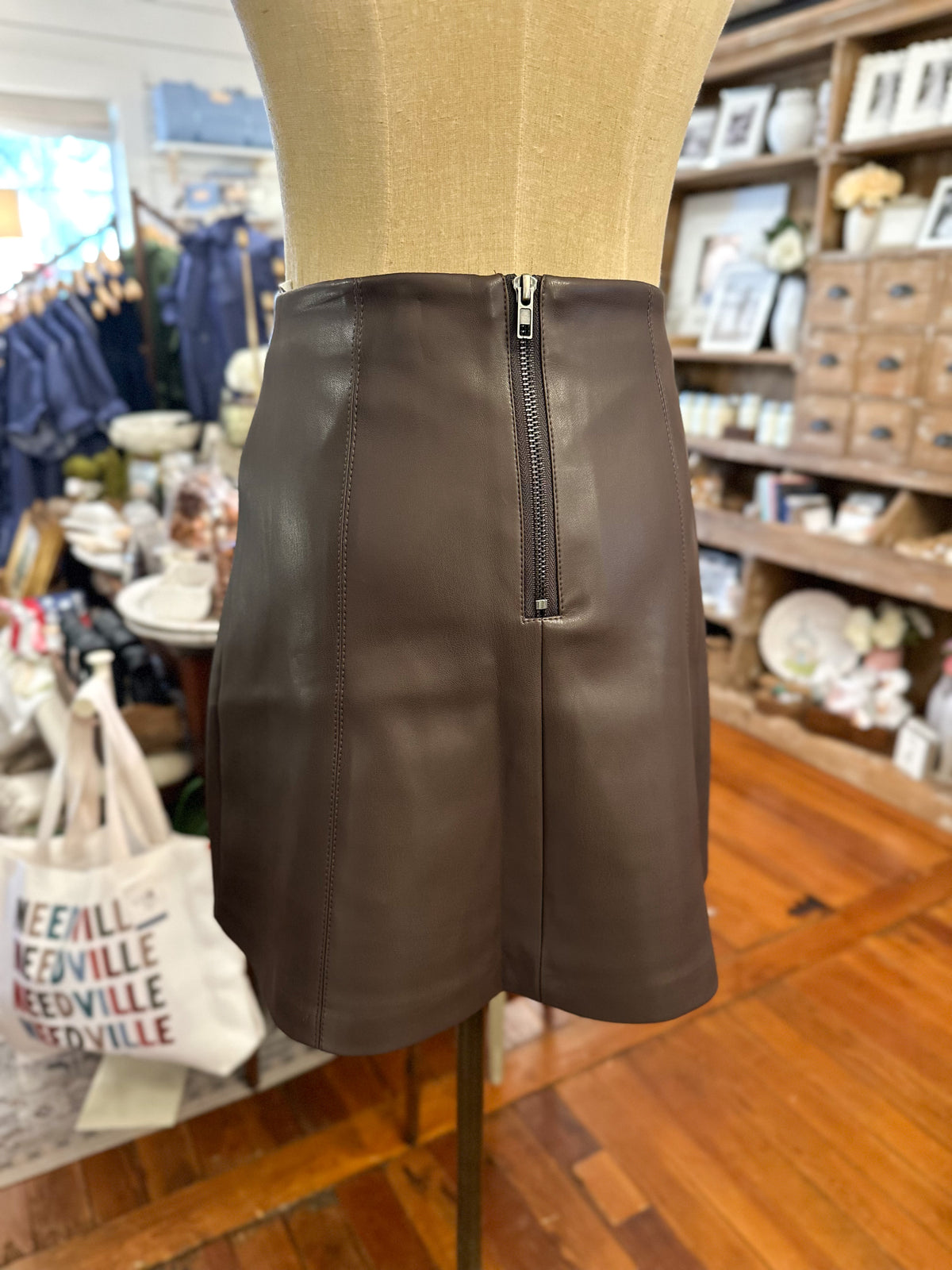 back of mini brown faux leather skirt inside boutique store 