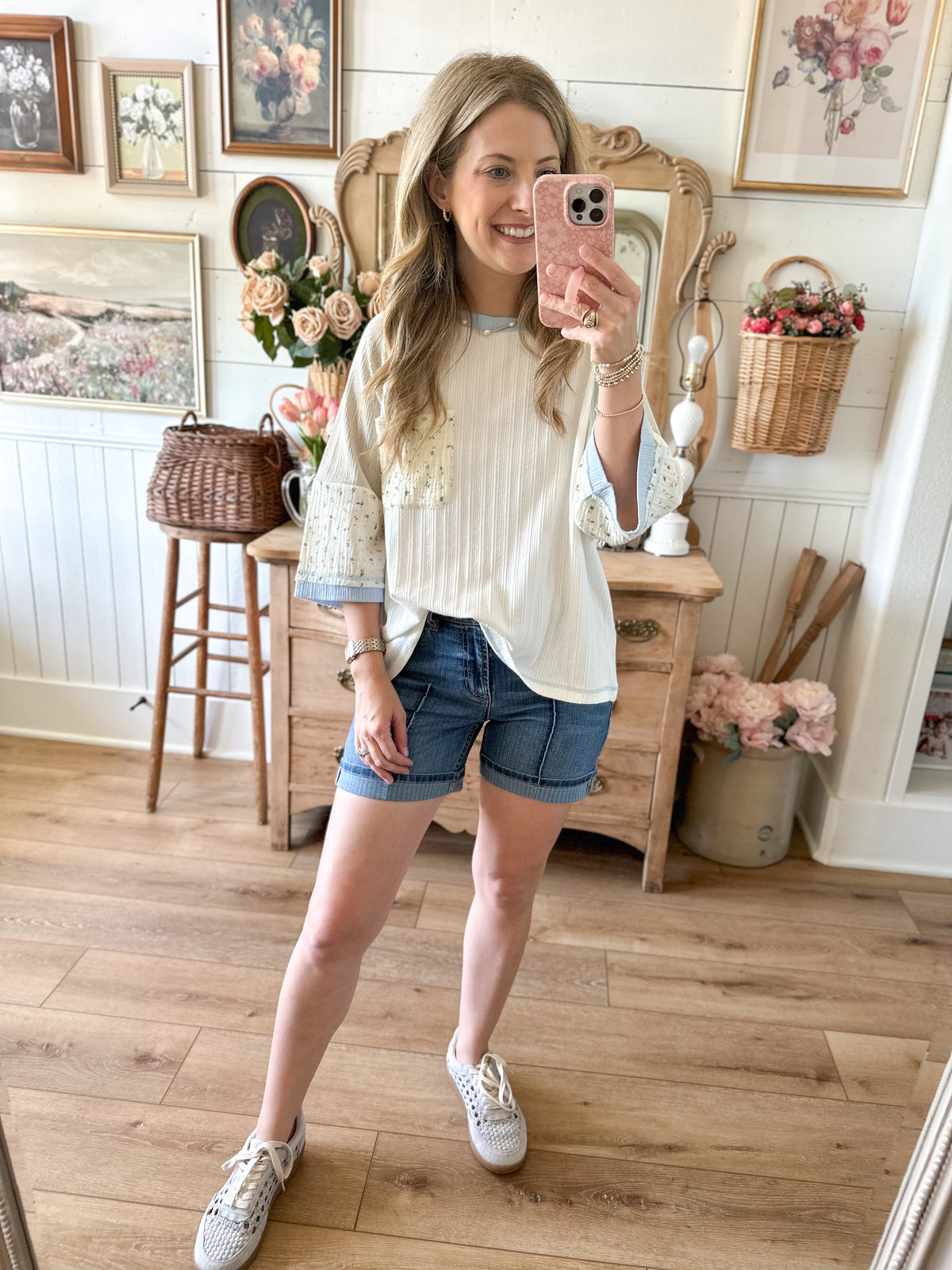Woman taking a mirror selfie in a room with wooden floors and decorative elements.