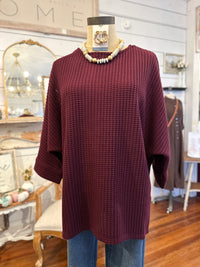 Maroon sweater on a mannequin with a blurred store interior background