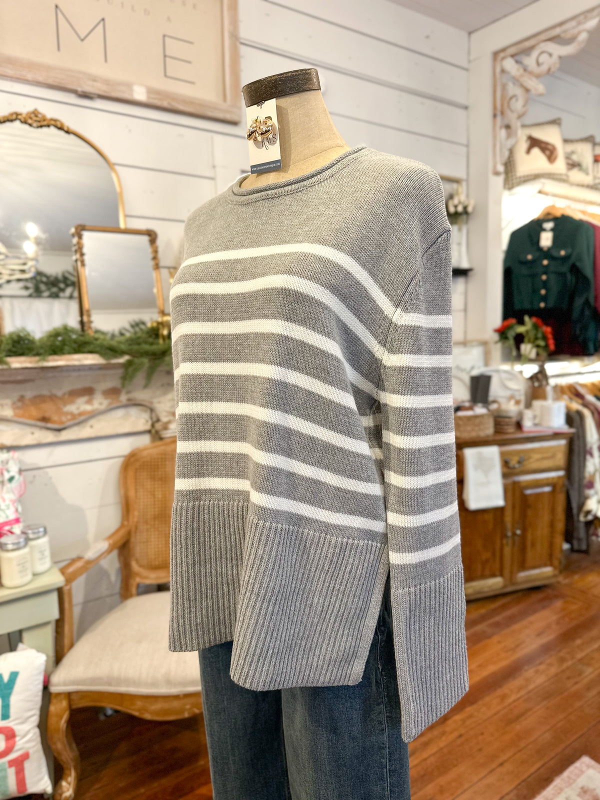 Mannequin wearing a gray and white striped sweater in a store setting