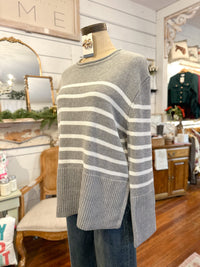 Mannequin wearing a gray and white striped sweater in a store setting