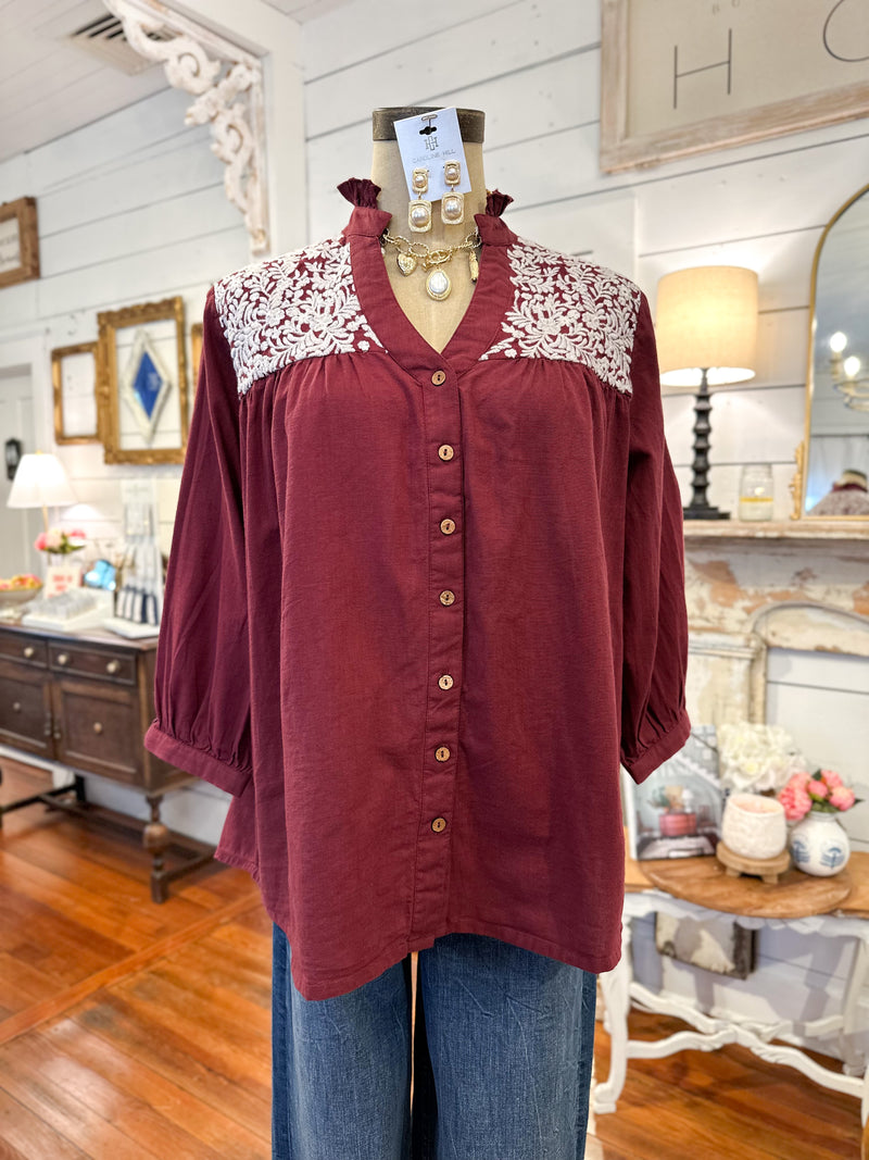 Maroon blouse with lace details on a mannequin in a store setting