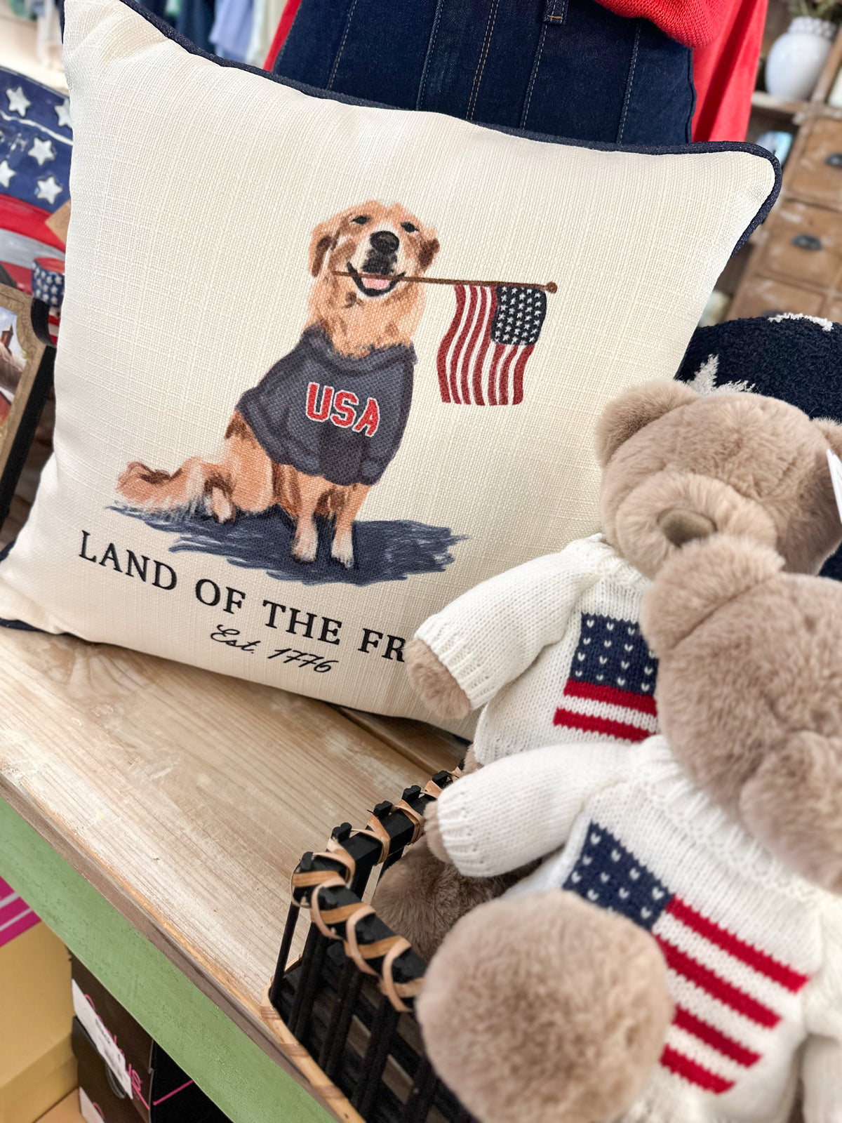 Pillow with a dog illustration and American flag, surrounded by other items on a table.