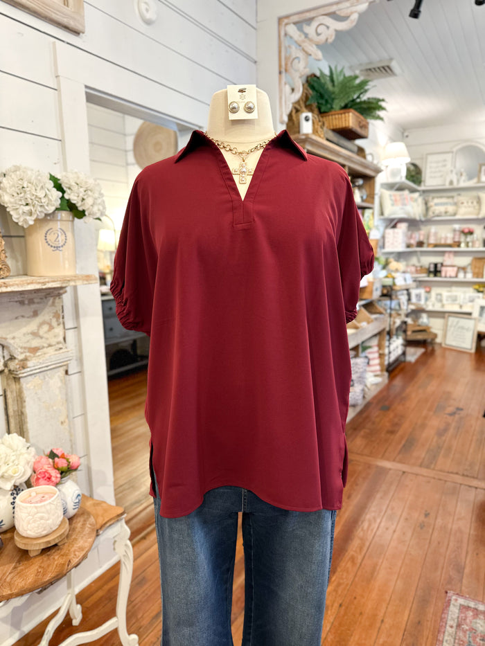 Mannequin wearing a burgundy shirt and blue jeans in a store setting
