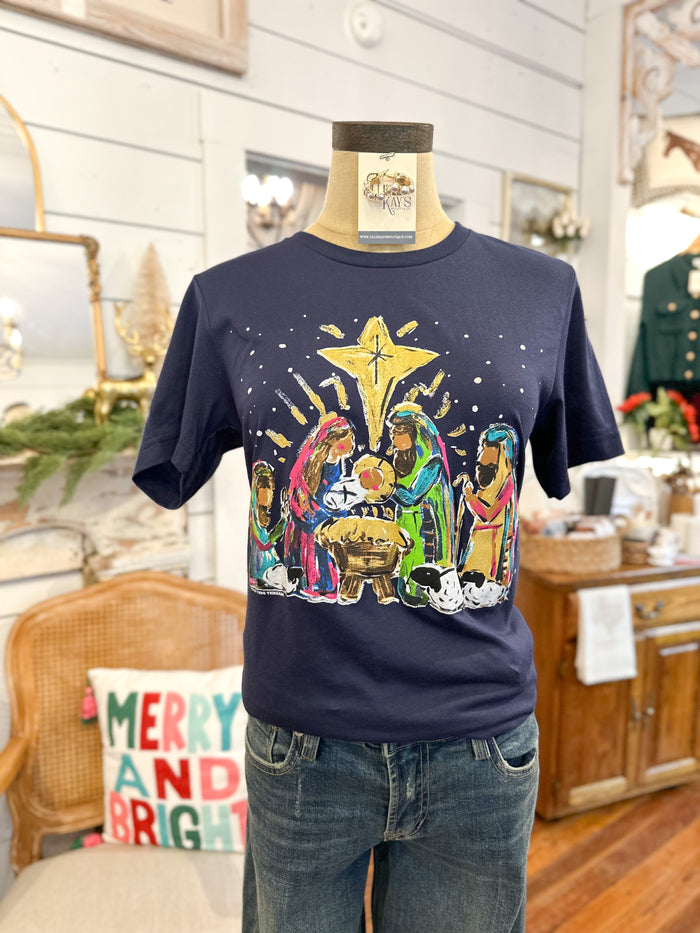 Navy blue t-shirt with nativity scene design on a mannequin against a home interior background.