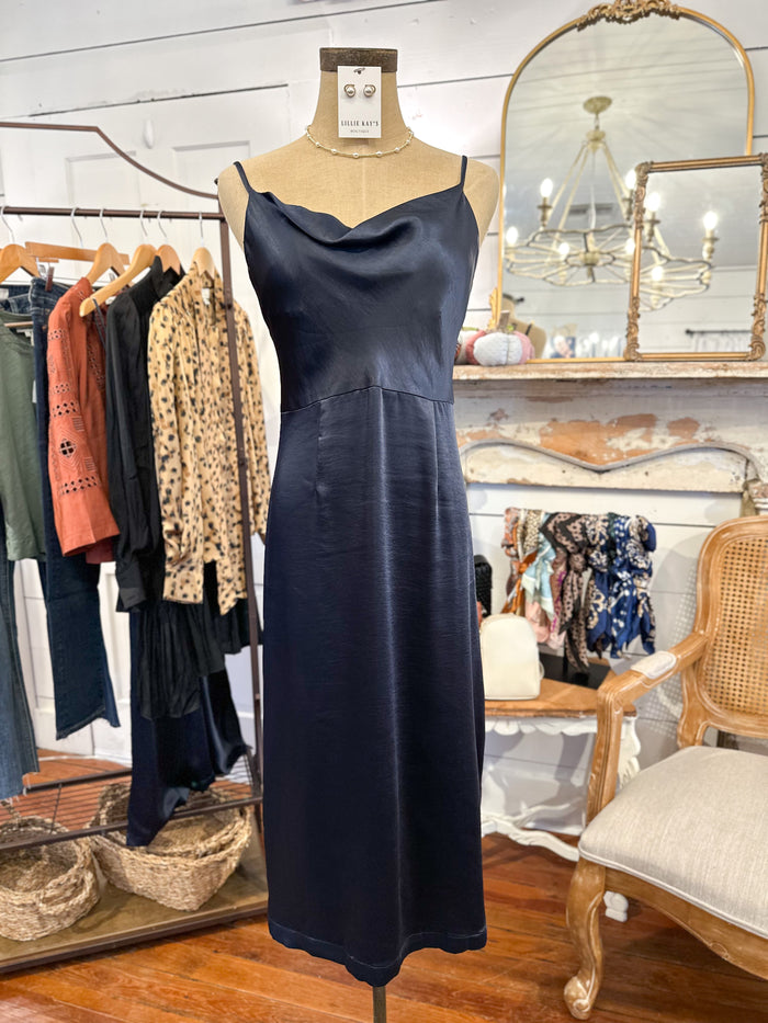 Navy blue dress on a mannequin in a clothing store setting with mirrors and other garments.