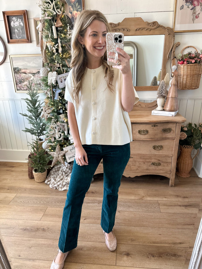 Woman taking a mirror selfie in a room with a Christmas tree and wooden furniture.