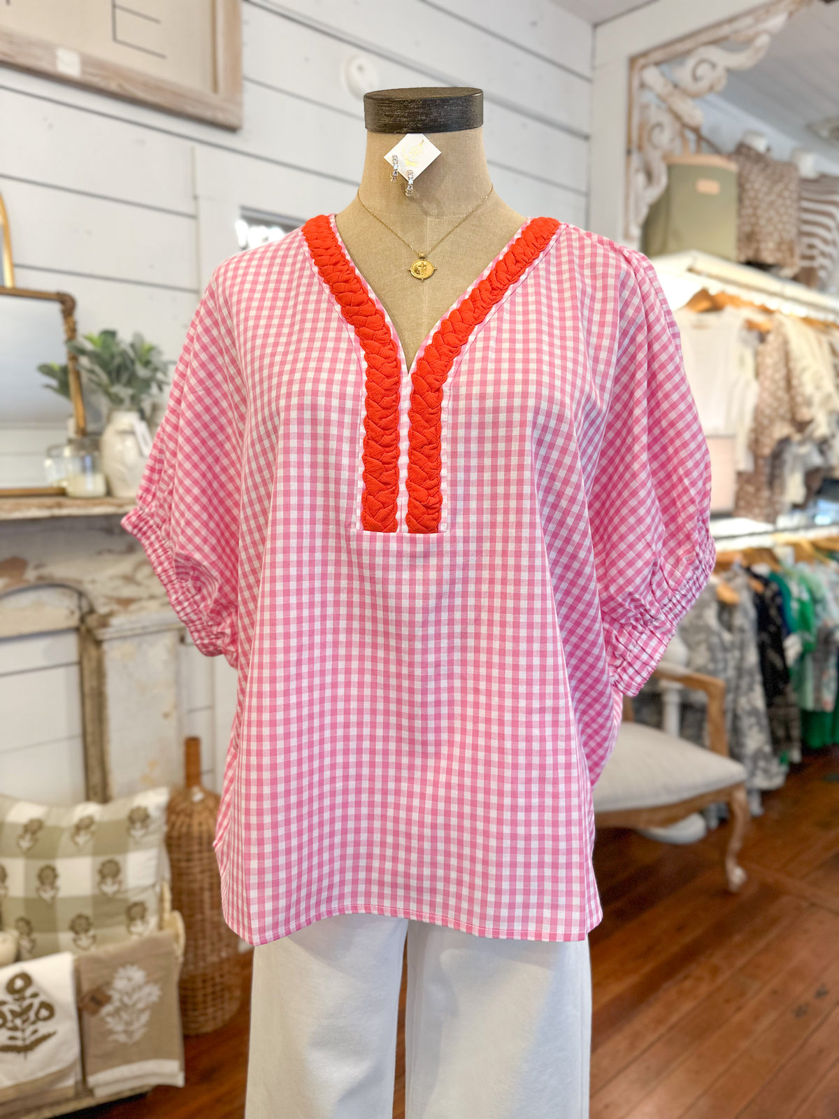 Pink checkered blouse with orange trim on a mannequin in a store setting
