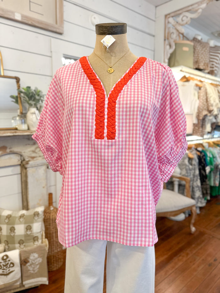 Pink checkered blouse with orange trim on a mannequin in a store setting