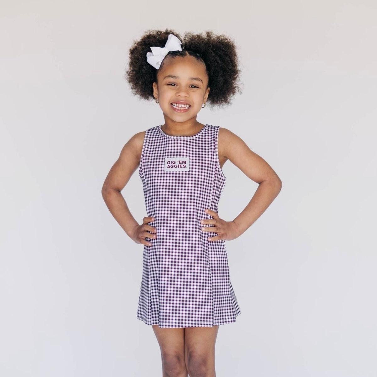 Young girl wearing a checkered dress with text on a plain background