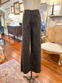 Leopard print pants on a mannequin in a store setting with wooden floor and furniture.