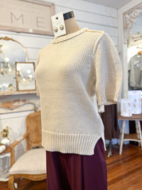 Beige sweater on a mannequin in a store setting with decor elements.