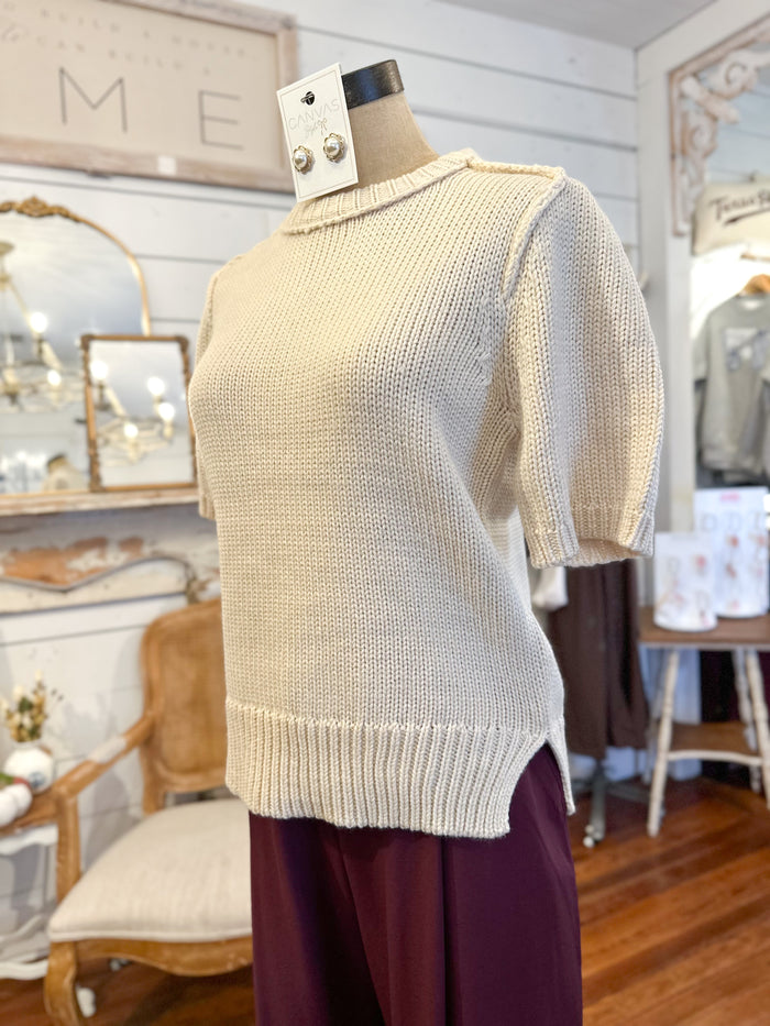Beige sweater on a mannequin in a store setting with decor elements.