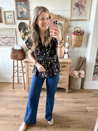 Woman taking a mirror selfie in a room with wooden floors and decorative elements.