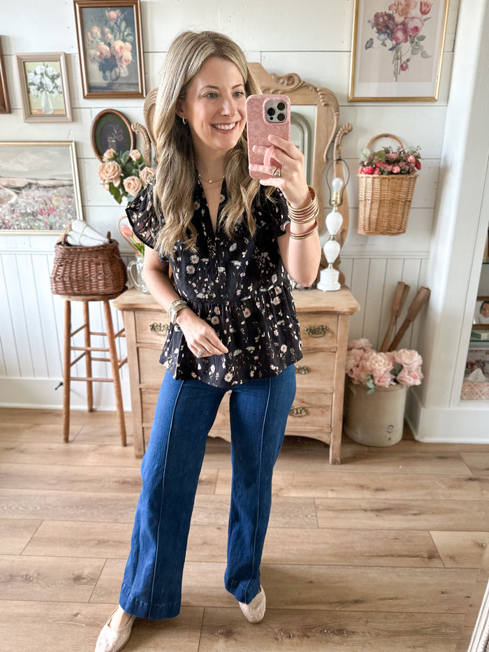 Woman taking a mirror selfie in a room with wooden floors and decorative elements.