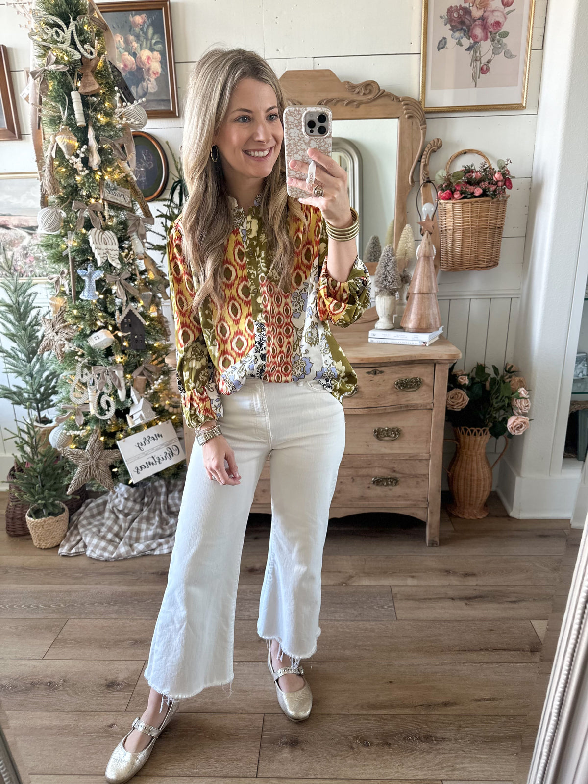 Woman taking a mirror selfie in a decorated room with Christmas tree and decor. satin like printed top fall thanksgiving christmas 
