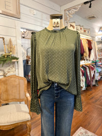 Green polka dot blouse on a mannequin in a store setting