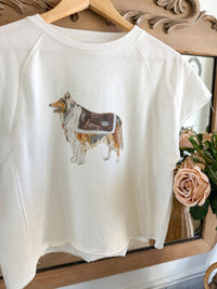 White sweatshirt with a dog graphic on a wooden hanger in front of a mirror.