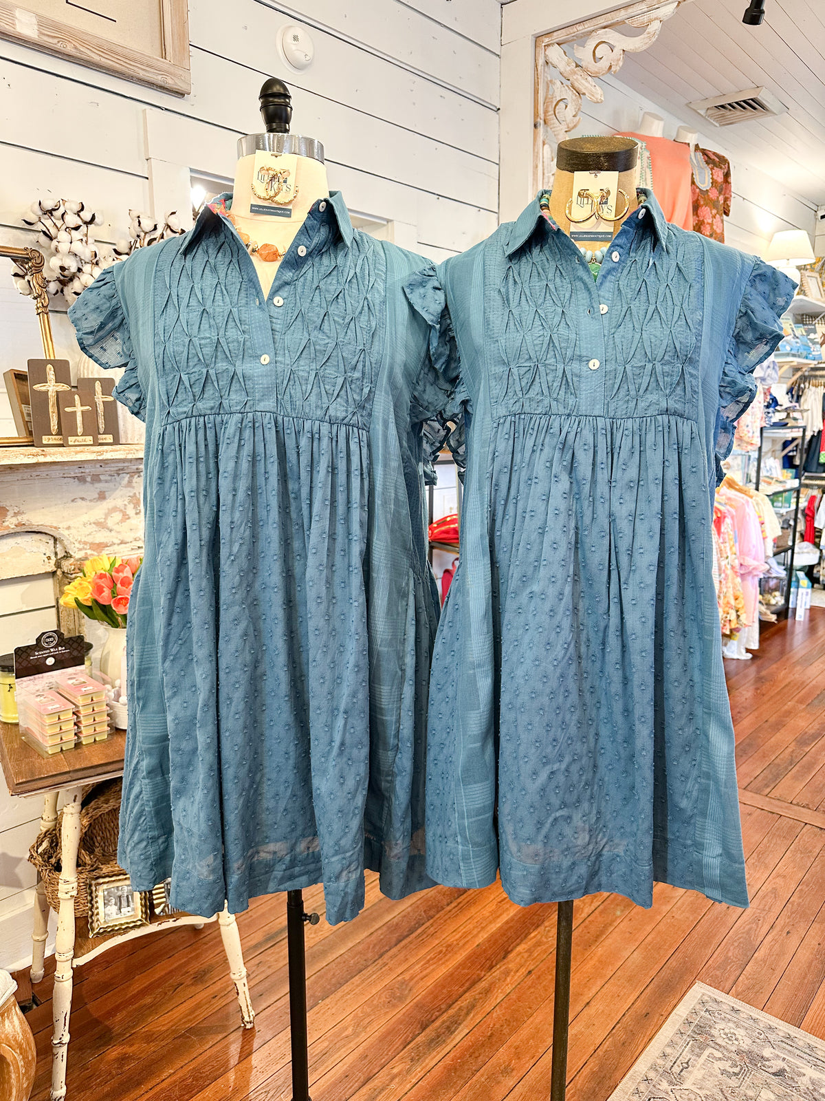 Two blue dresses on mannequins in a store setting.
