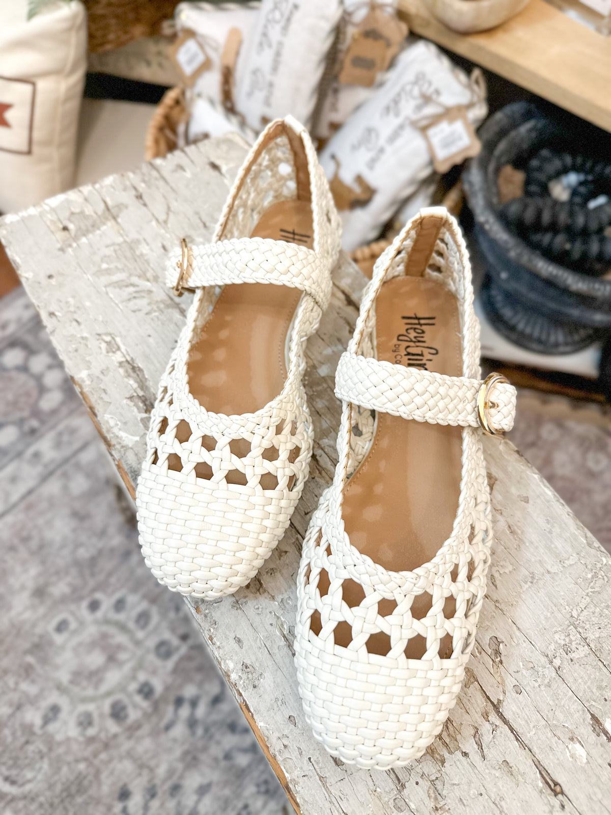 White woven shoes with a strap on a wooden surface