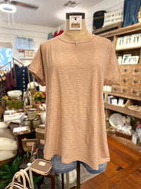 A short-sleeve crewneck t-shirt in a mauve color, displayed on a dress form mannequin inside a retail store.