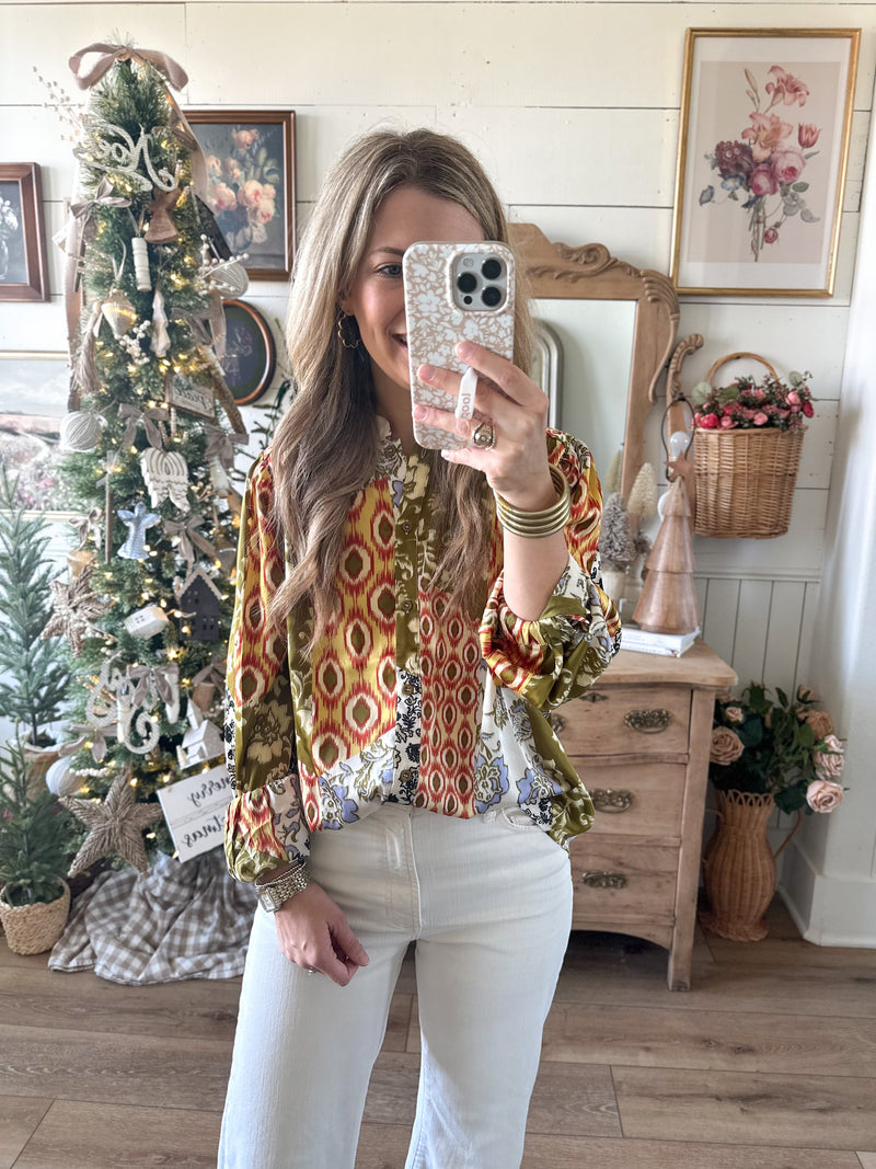 Woman taking a mirror selfie in a room decorated for Christmas with a tree and festive decor.