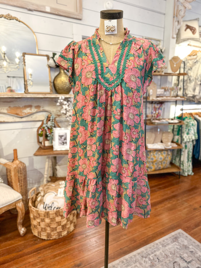 Floral dress on a mannequin in a store setting with shelves and decor in the background.
