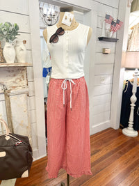 Mannequin wearing a white sleeveless top and red checkered pants in a store setting.