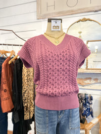 Pink knitted sweater on a mannequin with a blurred store interior background