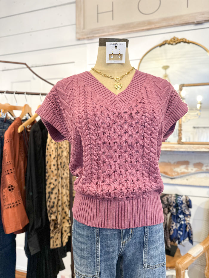 Pink knitted sweater on a mannequin with a blurred store interior background